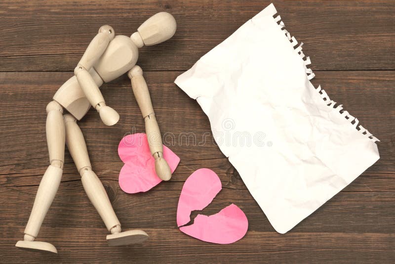 Wood Humane Figurine, Torn Blank Ð¡rumpled Paper Page And Two Broken Hearts On The Wood Background. Wood Humane Figurine, Torn Blank Ð¡rumpled Paper Page And Two Broken Hearts On The Wood Background